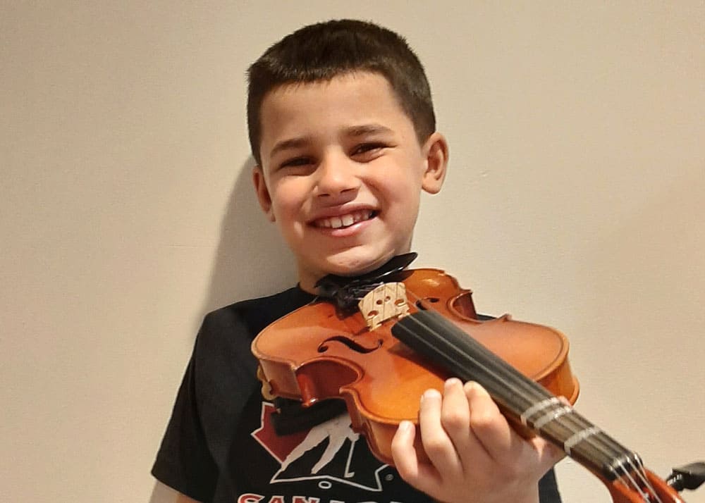 SJMA student smiling and holding a violin