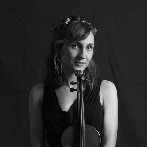 Headshot of Irene Senent wearing a flower crown with a violin